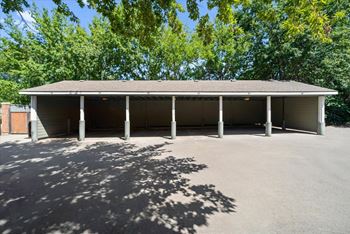 A large building with a grey roof and pillars is surrounded by trees. at Somerset Oaks Apartment Homes, Olathe